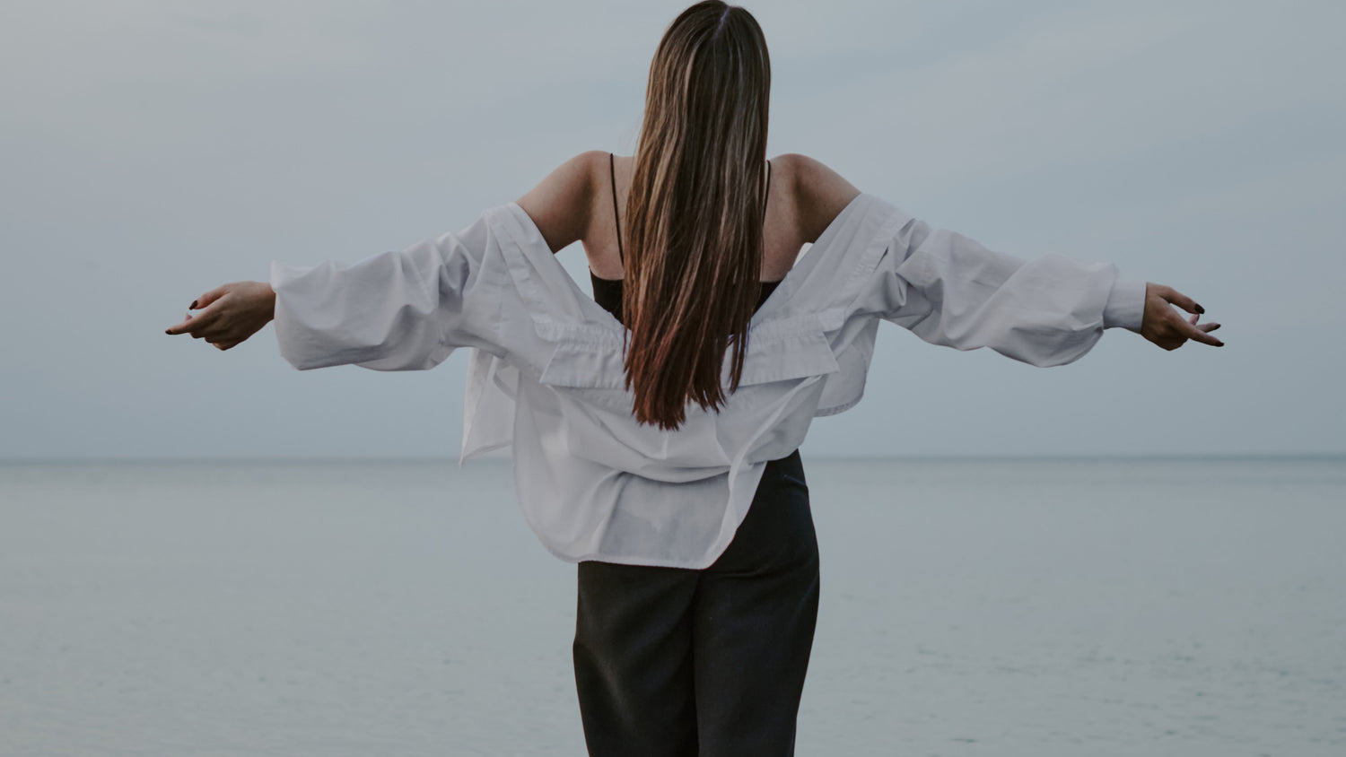 Woman with her arms outreached on the beach.