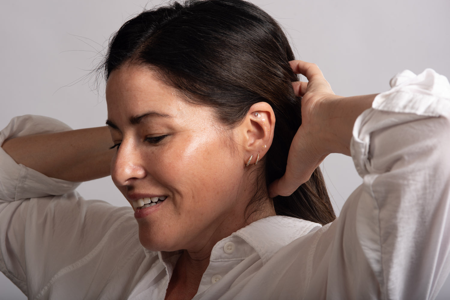 Woman holding back hair to show ear seeds for neck, back tension