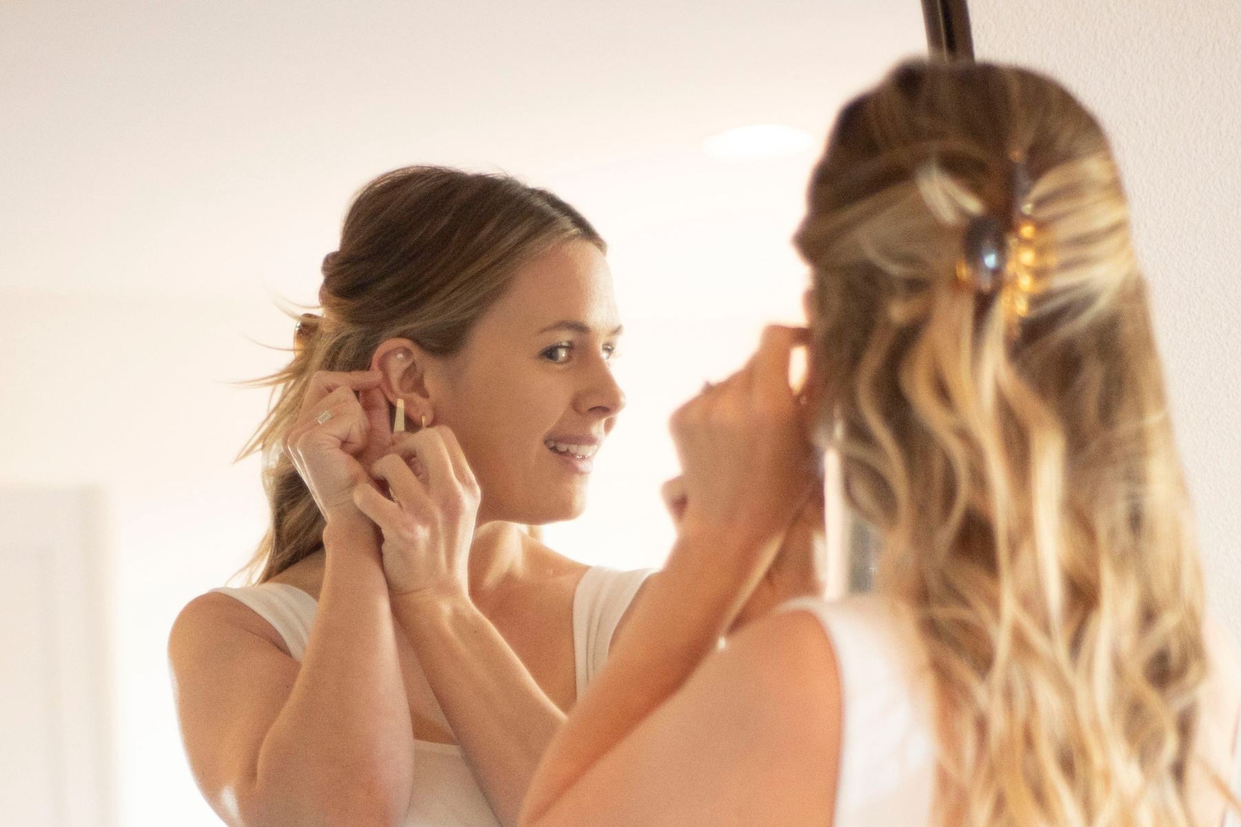 "Woman placing ear seeds on her ear while looking into a mirror"